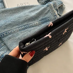 Detailed view of black quilted pouch with pink bow embroidery and smooth metal zipper