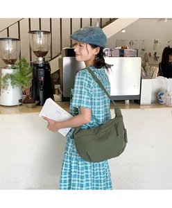 Detail of dark green canvas crescent bag showing large capacity for books in a cafe setting