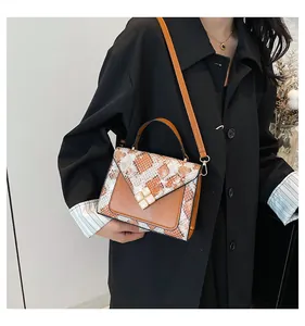 Detail view of a luxury snake print crossbody bag with square gemstone buckle and brown strap