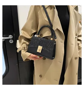 Detail of black glitter patchwork handbag with golden clasp worn with a trench coat