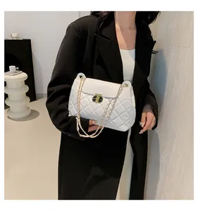 Sac bandoulière matelassé blanc avec chaîne porté par un mannequin pour un look quotidien