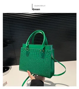 Detailed close-up of green crocodile-textured leather on a structured square tote bag