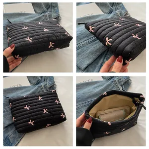 Detailansicht einer schwarzen gesteppten Kosmetiktasche mit rosa Schleifenstickerei und Reißverschluss