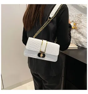 Weiße Umhängetasche mit Krokoprägung und goldener Kette an einem Model präsentiert