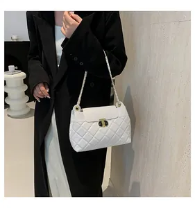 Détail du sac matelassé blanc avec chaîne et boucle en métal doré sur manteau noir
