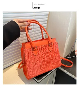 Detail showing bright orange crocodile texture tote bag with slim shoulder strap