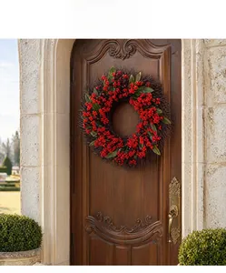 Detail of a Christmas berry wreath with red fruit and green leaves on a dark wooden door