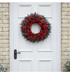 Christmas wreath with red berries and green leaves hanging on a white wooden door