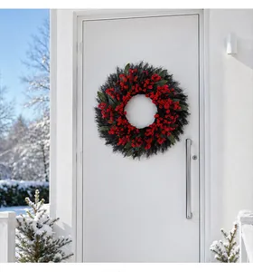 Christmas wreath with red berries on white door against a snowy outdoor background