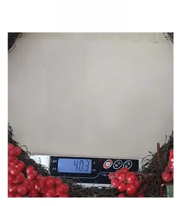 Christmas wreath with red berries being weighed on a scale to show the 403g net weight