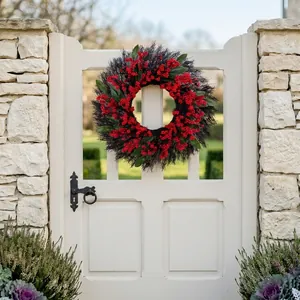 Christmas wreath with red berries and green leaves hanging on an elegant white wooden door