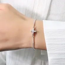 Detail of silver chain bracelet with a sparkling pavé-set cross pendant on the wrist