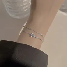 Close-up of double-layer silver bracelet with star pendants and sparkling crystal inlay