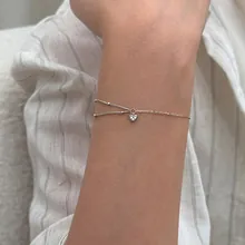 Close-up of minimalist silver double-layer chain bracelet with delicate heart pendant