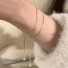 Detail of minimalist gold and silver snake chain bracelets with pearl accents on wrist