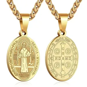 Close-up of double-sided gold Saint Benedict medal pendant with religious cross engraving