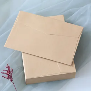 Stacked kraft paper envelopes with triangle flaps on a soft fabric background