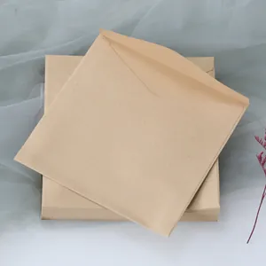 Macro shot of square kraft paper envelopes with triangular flaps and dry flower decor