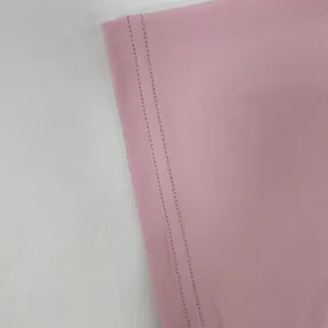 Gros plan des coutures à double aiguille sur l'ourlet de la robe moulante rose