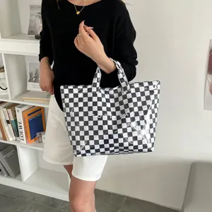 Close-up of checkerboard tote bag featuring bold TOTE BAG text and glossy PVC texture