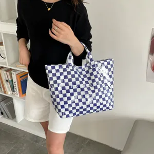 Detail shot of blue and white checkered tote bag in high-gloss finish with bold text