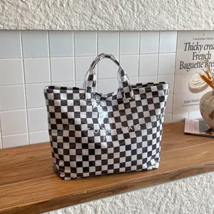 Detail of checkered tote bag with large capacity and glossy waterproof PVC texture