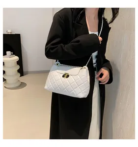 Sac à bandoulière matelassé blanc avec chaîne dorée et fermoir rotatif sur manteau noir