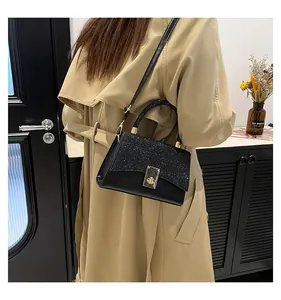 Model wearing black crossbody bag with sequin flap and gold lock over khaki trench coat