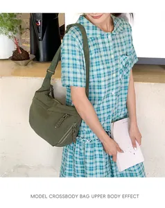 Model wearing a green corduroy crossbody bag with multiple zipper pockets and wide strap