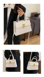 Détail d'un sac à main blanc à motif crocodile avec un fermoir en métal doré texturé