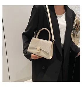 Detail of elegant cream handbag with sparkling diamond accents and golden twist lock