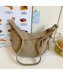 Close-up of beige corduroy crescent bag showing ribbed texture and zipper detail