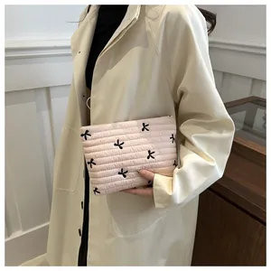 Detail of pink quilted handbag with black bow embroidery and soft textured finish