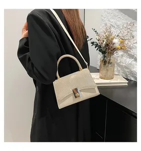 Detail of elegant rhinestone handbag with gold metal rotating lock and pearl white leather