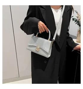 Detail of grey crossbody bag featuring a shimmering flap, silver glitter, and gold twist lock