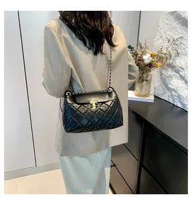 Détail du sac bandoulière en cuir matelassé noir avec chaîne dorée et fermoir pivotant
