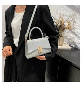 Detail of grey crossbody bag featuring sparkling silver glitter flap and gold twist lock