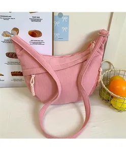 Detailed close-up of pink corduroy crescent bag with textured stripes and woven zipper pull
