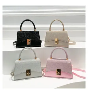 Detail of four chic square handbags in various colors featuring glitter texture and metal locks
