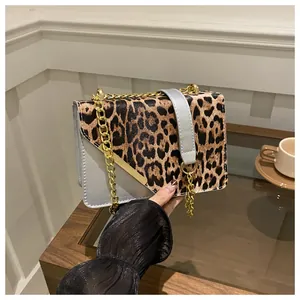 Dettaglio della borsa a tracolla con stampa leopardata, catena dorata e fibbia metallica