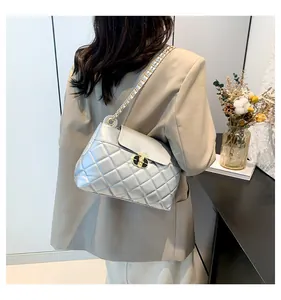 Détail d'un sac argenté matelassé à chaîne dorée porté sur un blazer beige chic