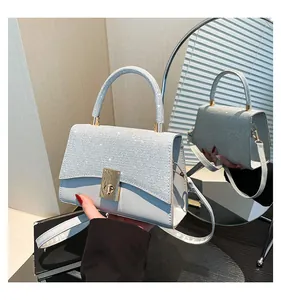 Detailed view of shimmering glitter textures and golden twist lock on a small silver square bag