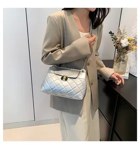 Détail du sac à main argenté matelassé avec bandoulière dorée porté par un mannequin