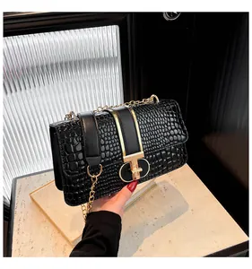 Detail der schwarzen Kroko-Handtasche mit goldenem T-Verschluss und Metallkette