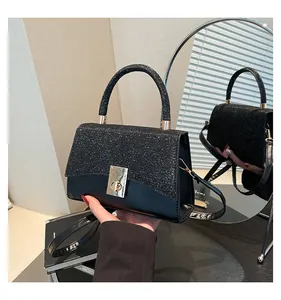 Detail of black sequined crossbody bag with gold twist lock and mirror reflection