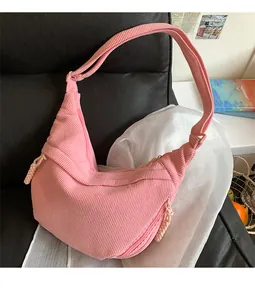 Detail of pink corduroy dumpling bag with double zippers and woven rope pulls