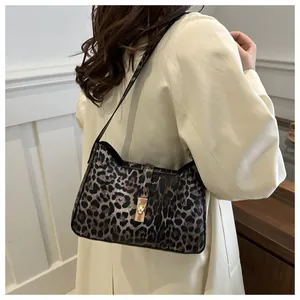 Detail view of stylish leopard print underarm bag with gold twist lock on trench coat