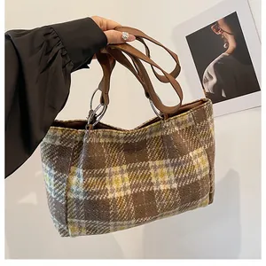 Detail der karierten Tweed-Tragetasche mit braunen Ledergriffen und silbernen Metallringen