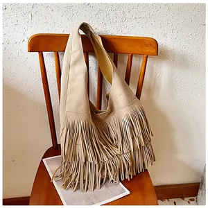 Detail van bohemien beige suède tote met dichte, dubbellaagse lange franjes op een stoel