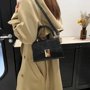 Minimalist black square handbag with sequins and gold buckle shown on a model